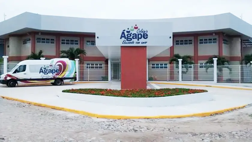 Fachada do prédio do Colégio Ágape na Cidade de Eusébio no Ceará, à frente da construção térrea, pode-se ver um totem vermelho com o logo e o nome da escola no topo